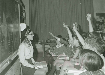 Elementary students learning from a teacher in the 1960s