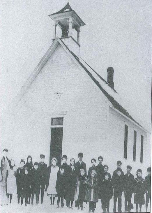 South School - White School house with bell tower and glass windows. School Children standing out front