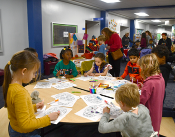 Children and adults participating in a coloring activity at a community event.