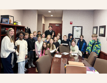   Group of students visiting an office, posing for a photo with an adult leader.