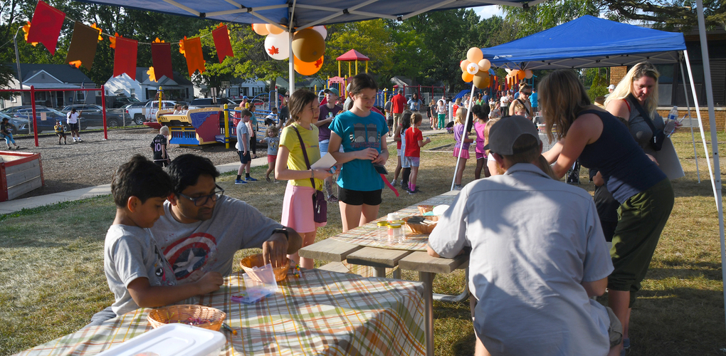 Community members enjoying a local outdoor event with food and decorations under a tent.