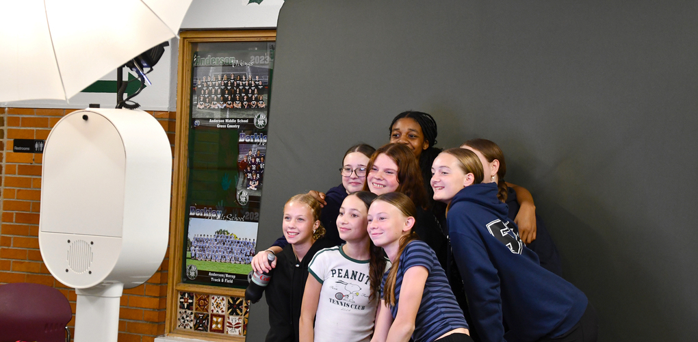 roup of students posing for a photo in front of a backdrop with a large umbrella light